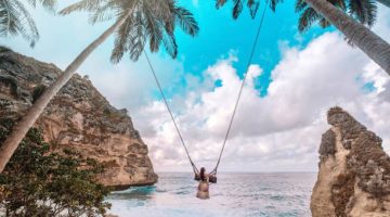 Beautiful girl on swing coconut palms on beach at Daimond beach, Nusa Penida island Bali ,Indonesia